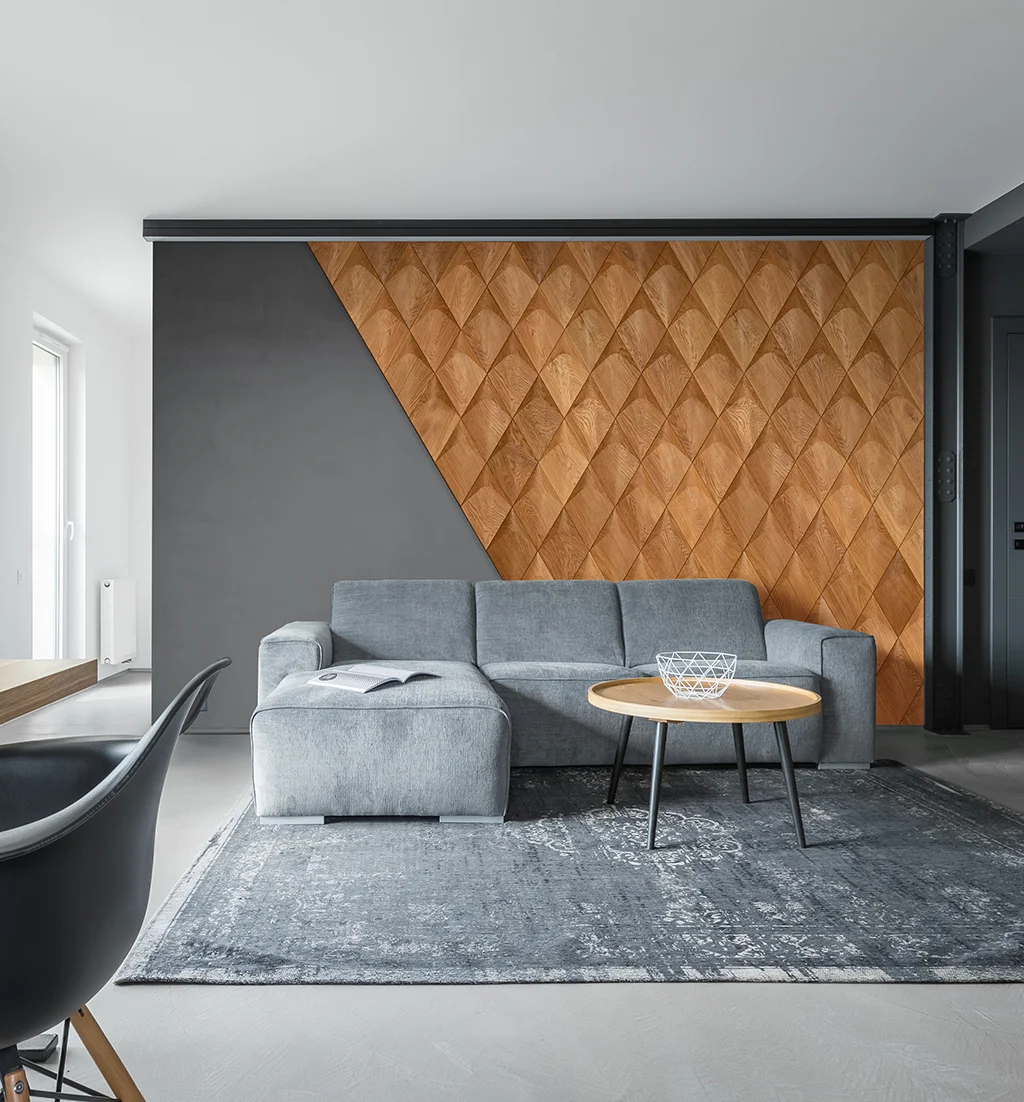 Modern living room with a grey sofa and geometric 3D oak wood wall panels in a diamond pattern.