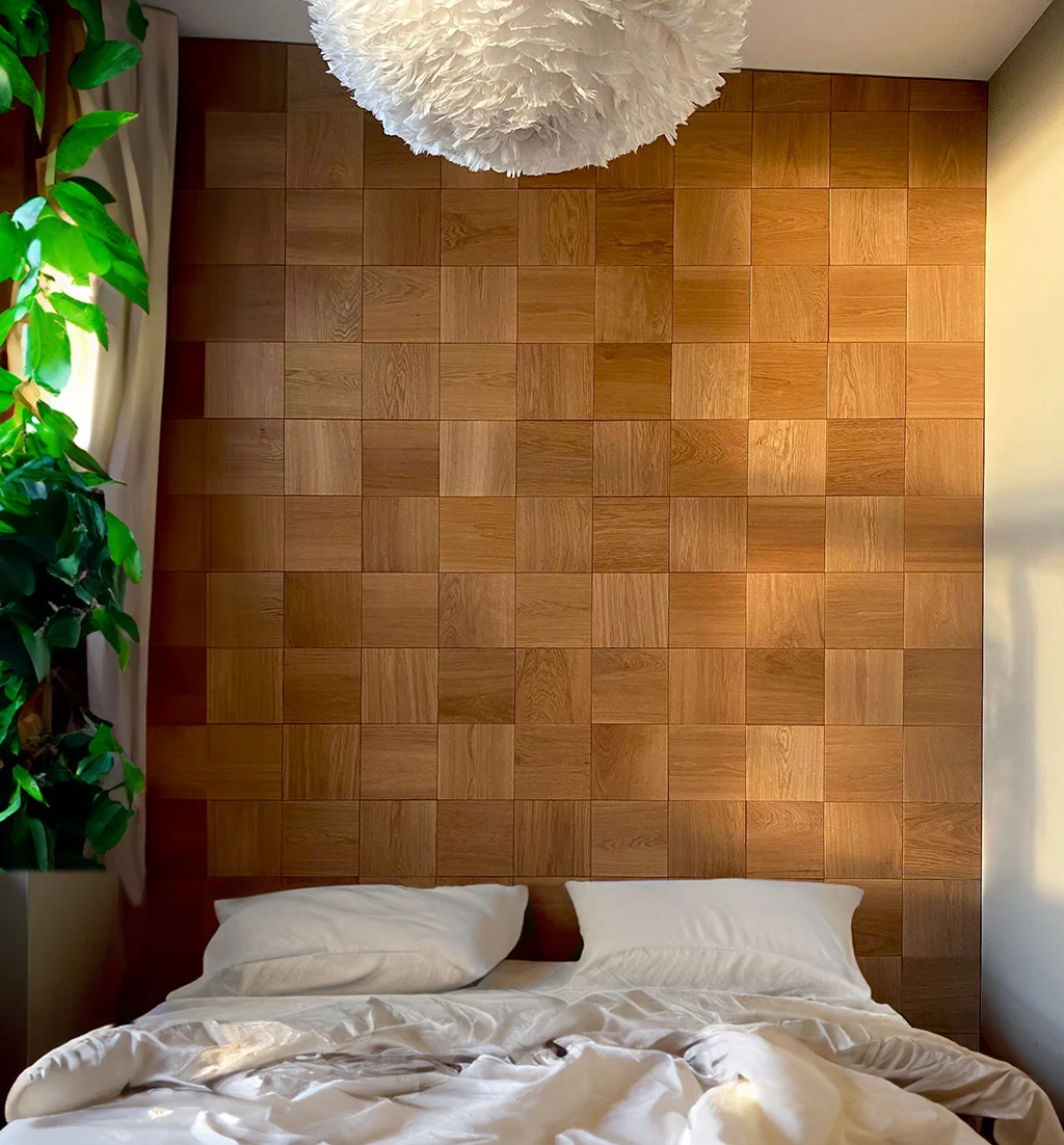 Cozy bedroom interior featuring a decorative accent wall behind the bed made of square oak wood panels.